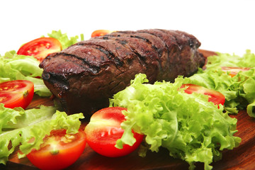 red roast meat served on wooden plate with vegetables