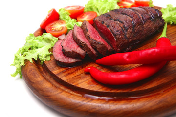 red roast meat served on wooden plate with vegetables