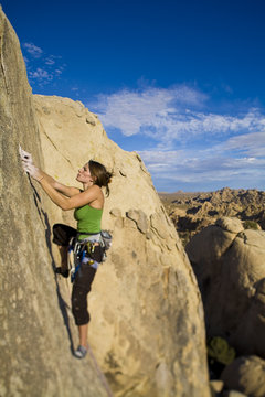 Female climber ascending a steep rock face.