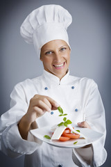 portrait of female chef, composing a cheese and tomato starter