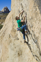 Climber ascending a steep rock face.