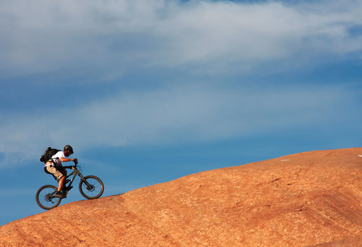 A lone mountainbiker rides a steep slickrock.