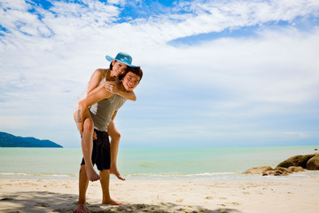 happy loving couple having fun piggyback at the sunny day beach