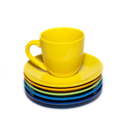 Yellow teacup and stack of saucers isolated on white.