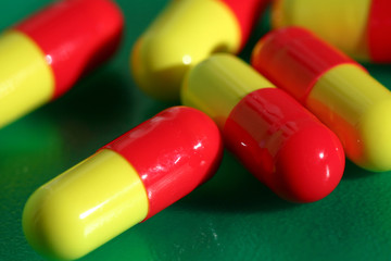 An image of yellow-red pills on green background