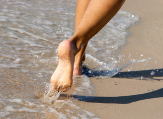 Women's barefoot legs on the beach