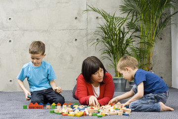 Obraz premium mother and two children and wooden blocks - relax time