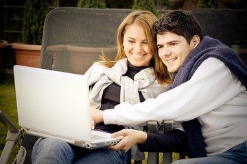 Happy Young couple surfing the internet outside