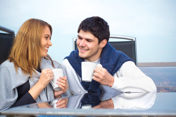 Fototapeta na wymiar Happy young couple having fun outside having a cup of coffee
