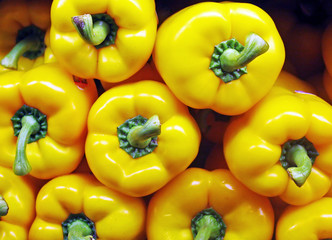 A display of yellow bell peppers in a vegetable market