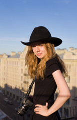 The young beautiful girl with the camera on a roof