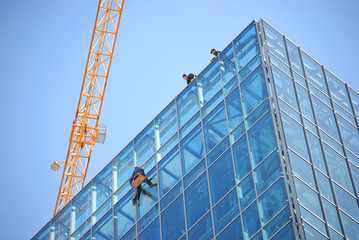 Building construction with crane with man washing glass windows
