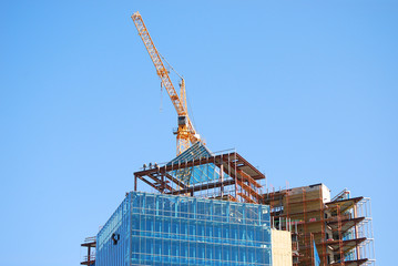 Building construction with crane and people on roof working