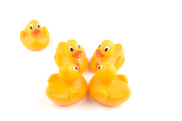 Four rubber ducks stand in a group with one isolated