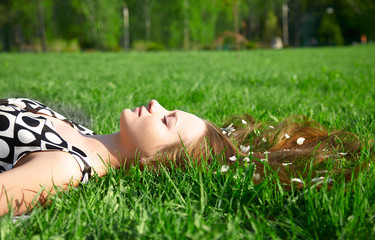 girl is laying on the grass with petals in hair