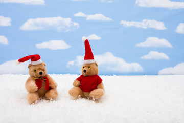 Stuffed bears wearing Santa hats on sky background