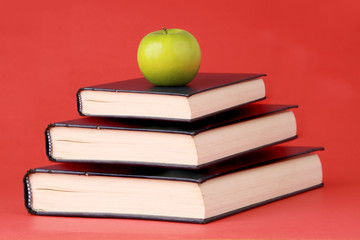 green apple and book, red background