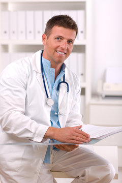 Happy male doctor working at office, smiling.