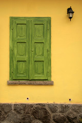Vintage photo of closed green shutters and yellow facade