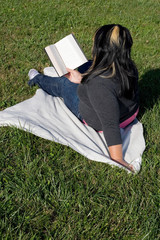 A young woman with highlighted hair reading a book