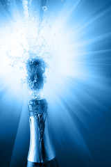 Bottle of champagne with splashes over blue background