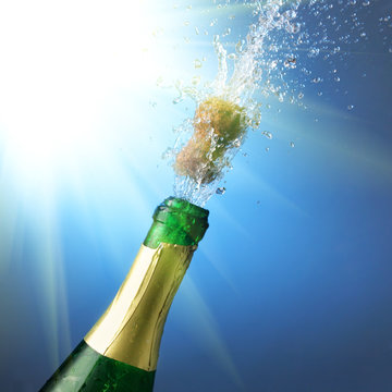 Bottle of champagne with splashes over blue background
