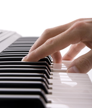 A musicians hand on a keyboard isolated on white