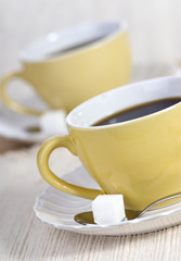 Two fresh cups of morning coffee with one lump of sugar.