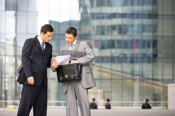 hommes d'affaires négotiant un contrat devant immeuble