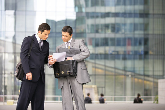 hommes d'affaires n&eacute;gotiant un contrat devant immeuble