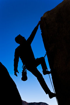 Climber clinging to  an overhanging rock face.