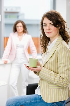 Young businesswomen having break at office drinking coffee.