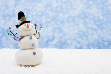 Snowman sitting on snow with snowflake background
