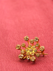 Golden brooch over pink background