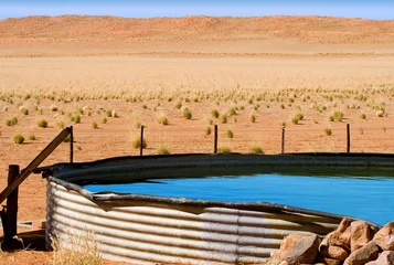 Fotobehang corrugated iron dam with cool blue water on desert farm © lienkie