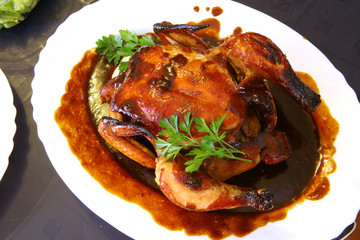 Roast chicken on a white plate with brown sauce