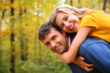 Young blond embraces man from back.