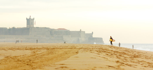 Beach with coastal fortification and a surfer in the distance