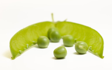 Green peas in front of open pod isolated on white
