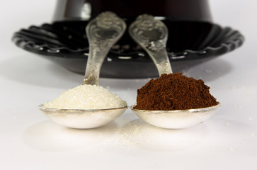 Two  tea-spoon with coffee and sugar infront of cofee-cup