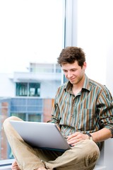 Young casual office worker sitting at office window working