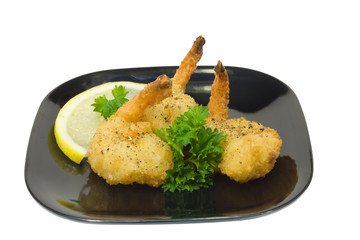 trio of fried shrimp with parsley on a black plate