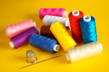 sewing.thread coils, thimble and a needle
