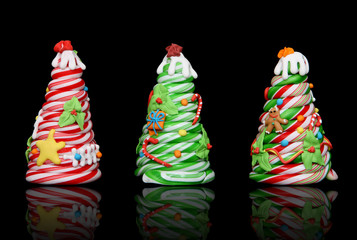 Three colorful candy cane Christmas trees over black background