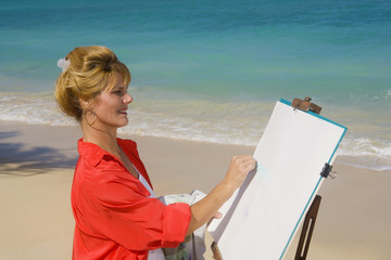 Obraz premium A female artist painting on the beach in Hawaii