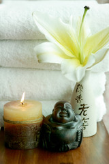 Candle, Buddha, lily and white towels at spa