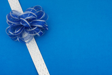 White ribbon and blue bow on blue