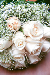 Two gold wedding rings on a bouquet white flowers