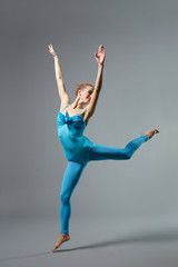 Fototapeta na wymiar young beautiful ballerina posing on grey background