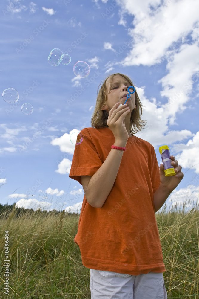 Wall mural Children blowing bubbles on summer meadow